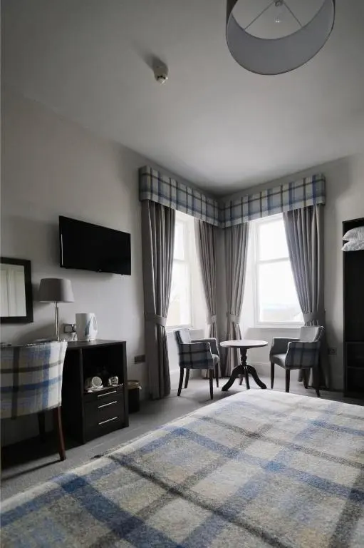 a living room with a table and chairs and a tv at Fife Lodge Hotel in Banff