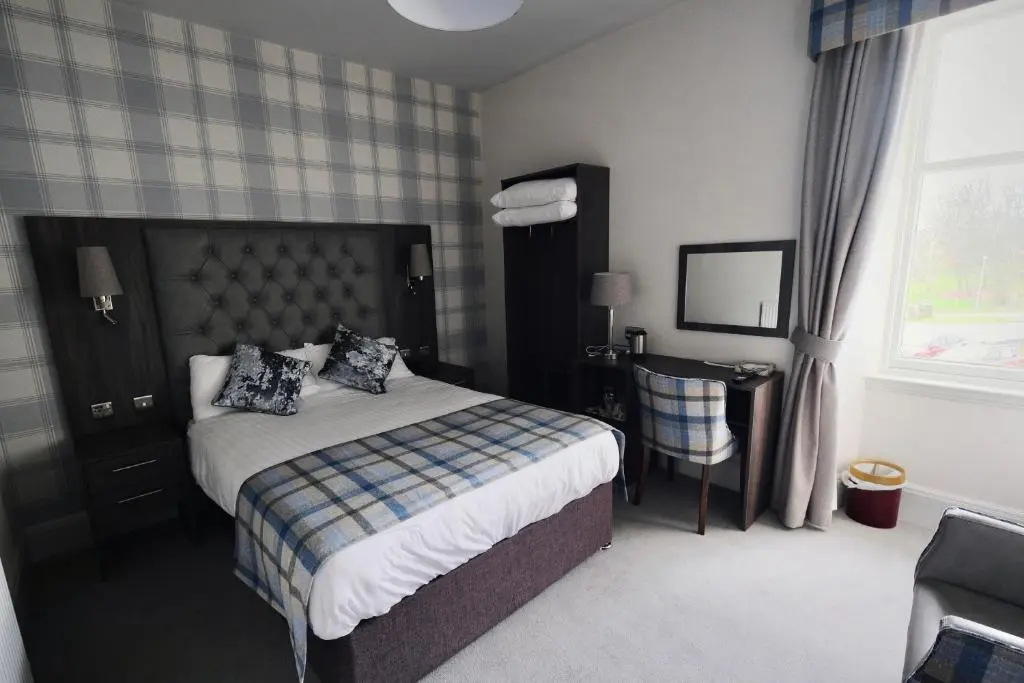 a bedroom with a bed and a desk and a window at Fife Lodge Hotel in Banff