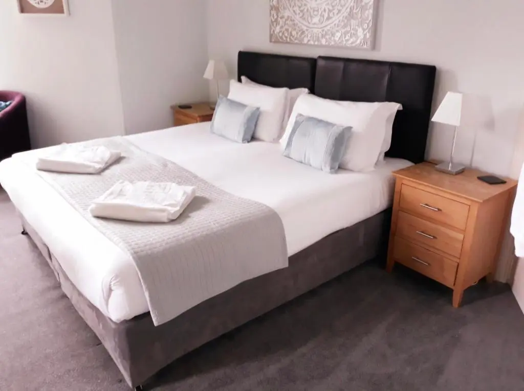 a bedroom with a large bed with two towels on it at Kinnaird Country House with Hot Tub in Pitlochry
