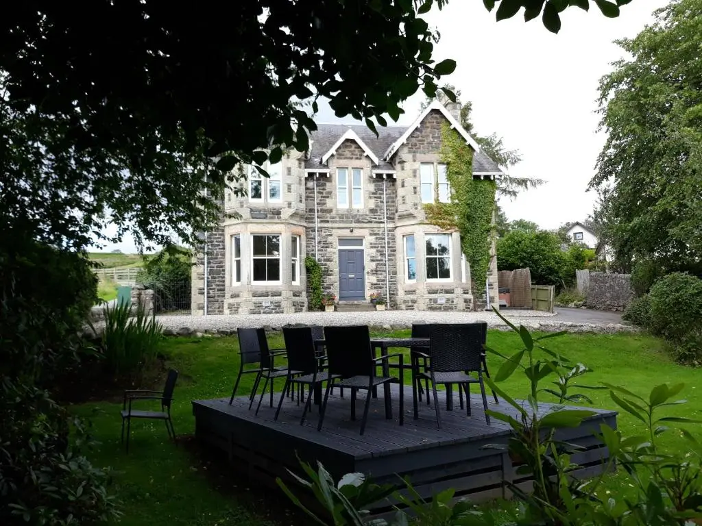 a table and chairs in front of a house at Kinnaird Country House with Hot Tub in Pitlochry