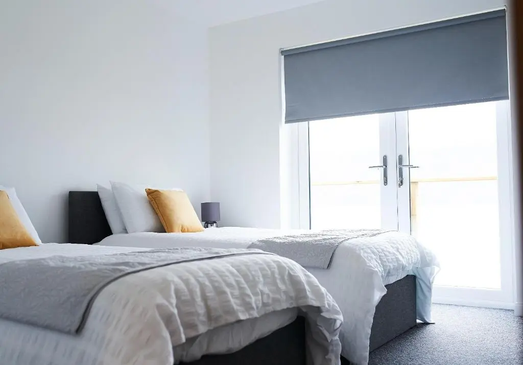 a white bedroom with two beds and a window at Shoreland Lodges - Holly Lodge in Fort Augustus