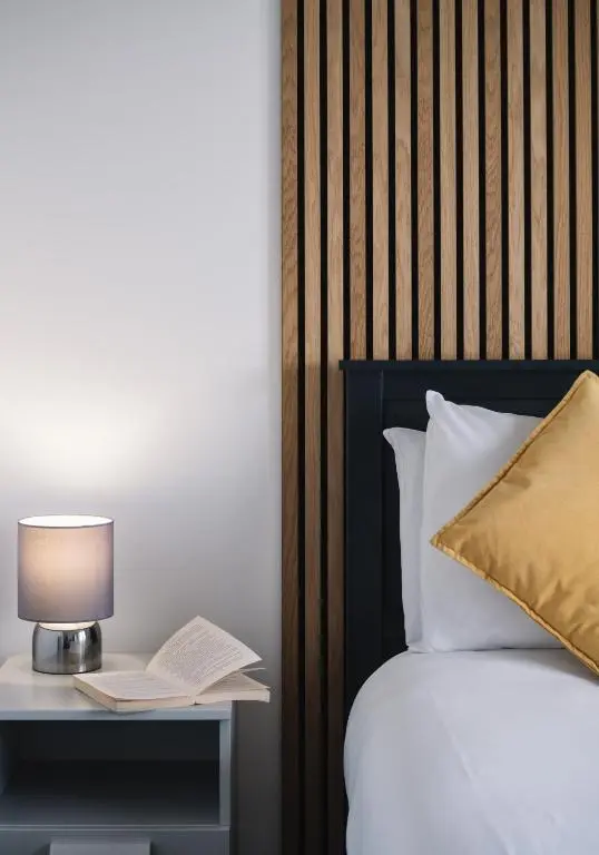 a bed with a table with a lamp and a book at Shoreland Lodges - Holly Lodge in Fort Augustus