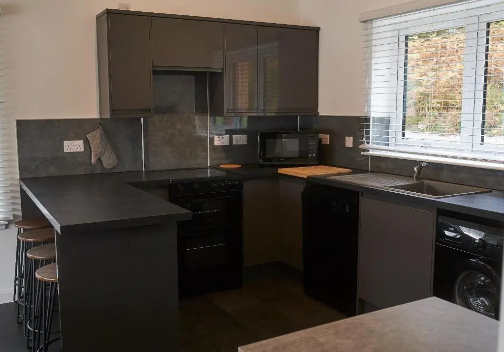 a kitchen with black cabinets and a sink at Shoreland Lodges - Cherry Lodge in Fort Augustus