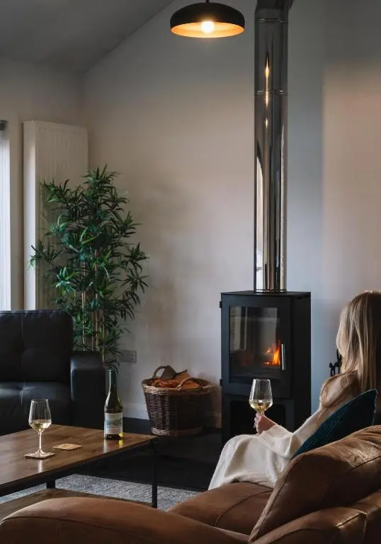 a woman sitting on a couch with a glass of wine at Shoreland Lodges - Cherry Lodge in Fort Augustus