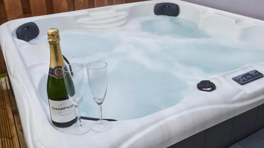 a bottle of champagne and two glasses in a bath tub at Shoreland Lodges - Cherry Lodge in Fort Augustus