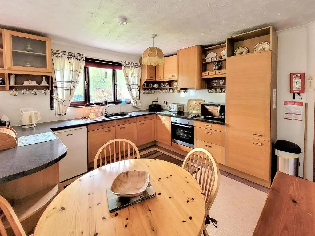 a large kitchen with a wooden table and chairs at The Birches in Ardclach