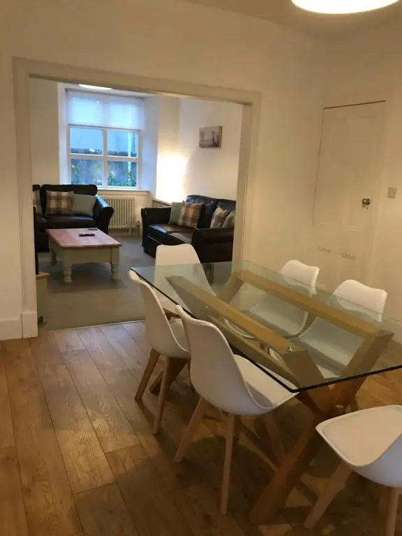 a living room with a glass table and white chairs at Fantastic central location in Inverness