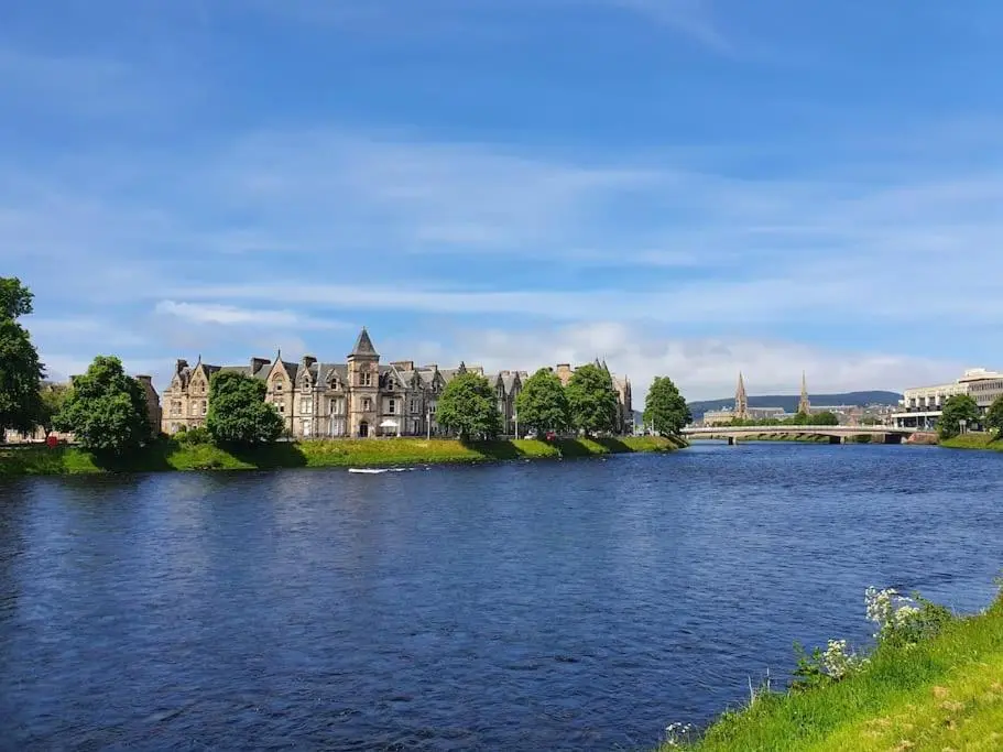 a large building sitting on the side of a river at Highland Historical Home in Inverness City Centre in Inverness