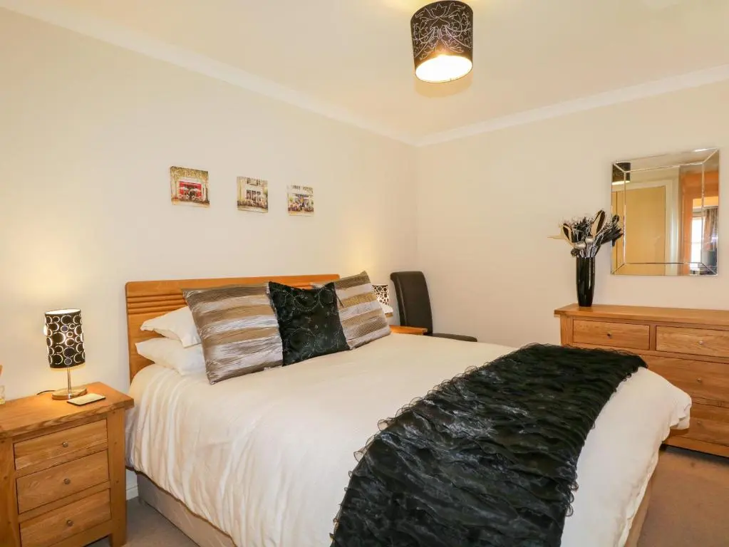 a bedroom with a bed and a dresser and a mirror at 7 Riverside Gardens in Inverness