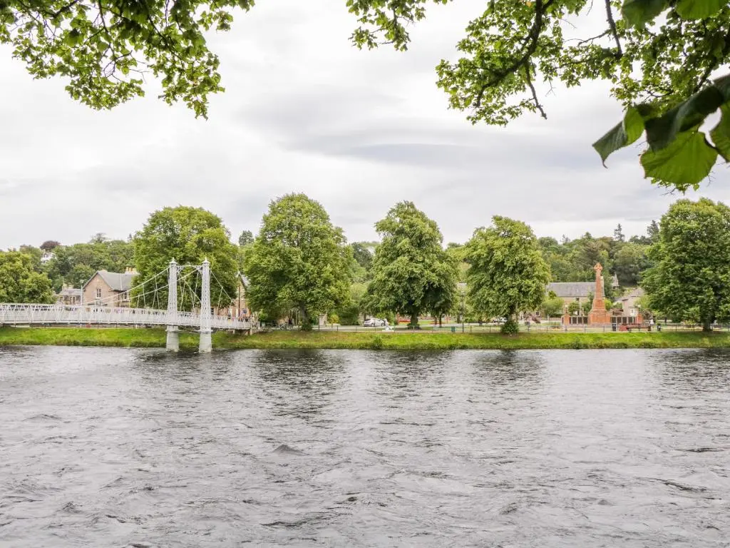 a bridge over a river with trees and buildings at 7 Riverside Gardens in Inverness