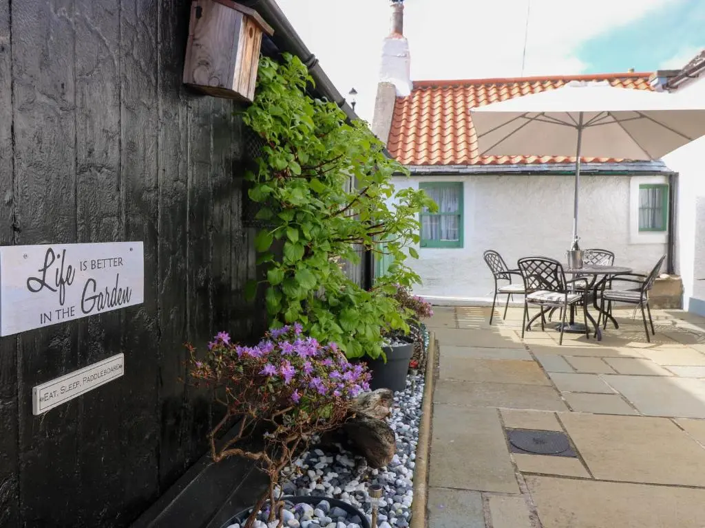 a patio with a table and chairs and an umbrella at 61 Seatown in Buckie