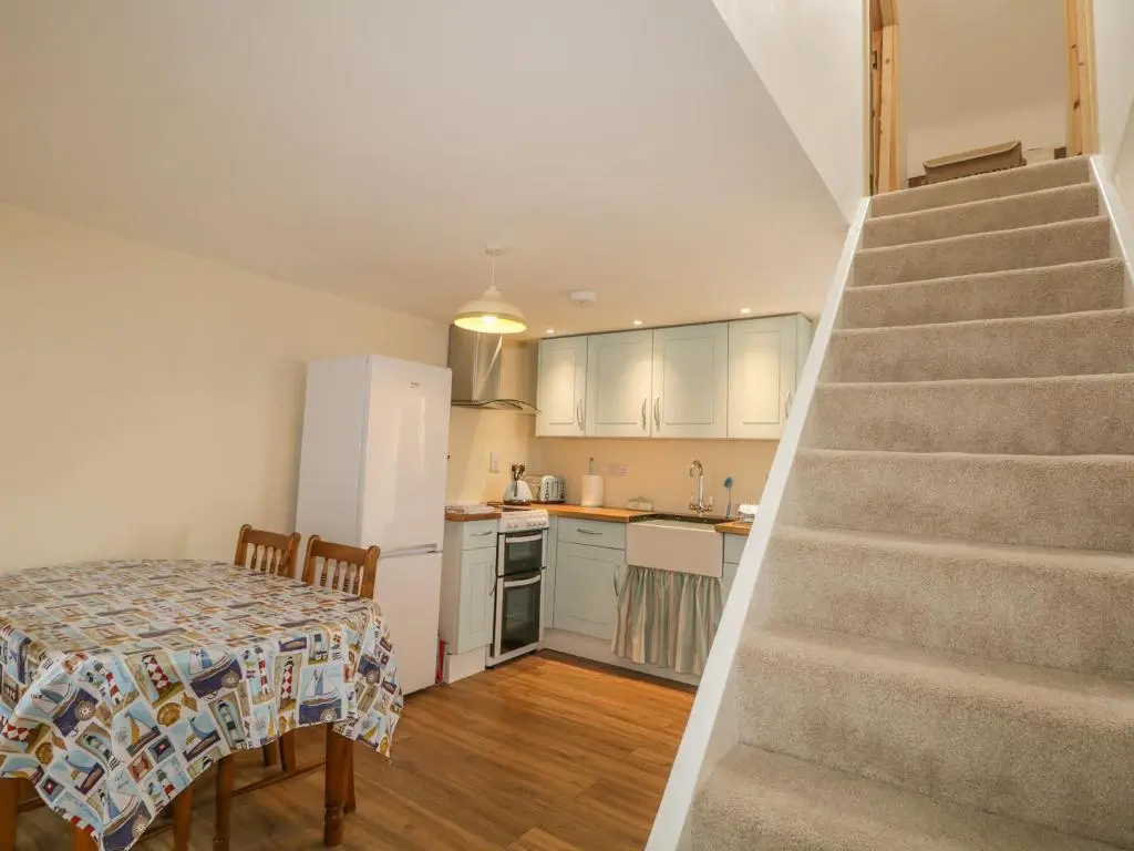 a kitchen with a table and a staircase leading up to a kitchen at 11 Village in Banff