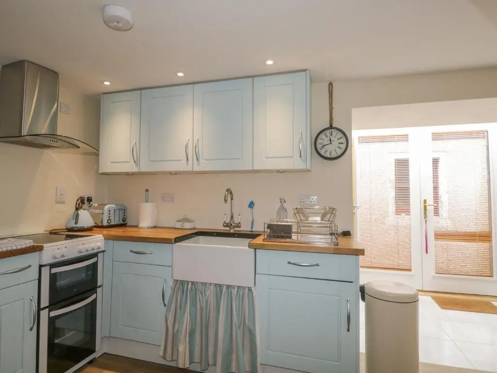 a kitchen with white cabinets and a clock on the wall at 11 Village in Banff