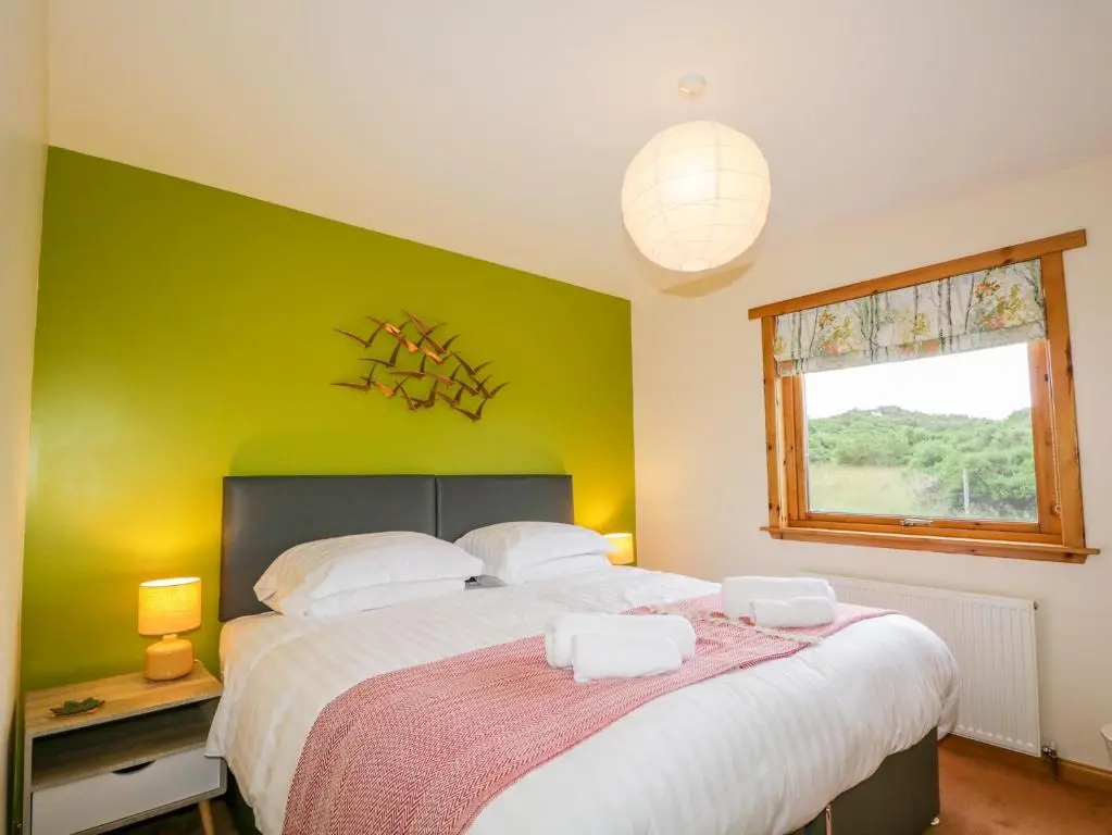 a bedroom with a large bed with a green wall at Ptarmigan in Carrbridge