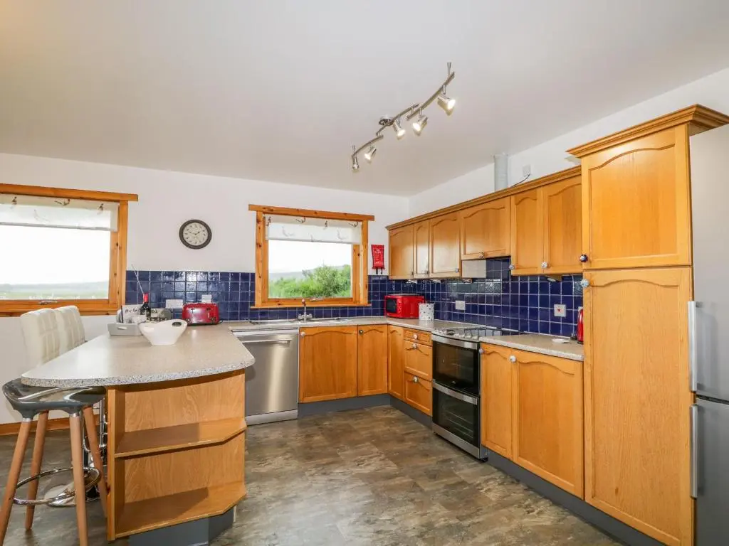 a kitchen with wooden cabinets and a counter top at Ptarmigan in Carrbridge