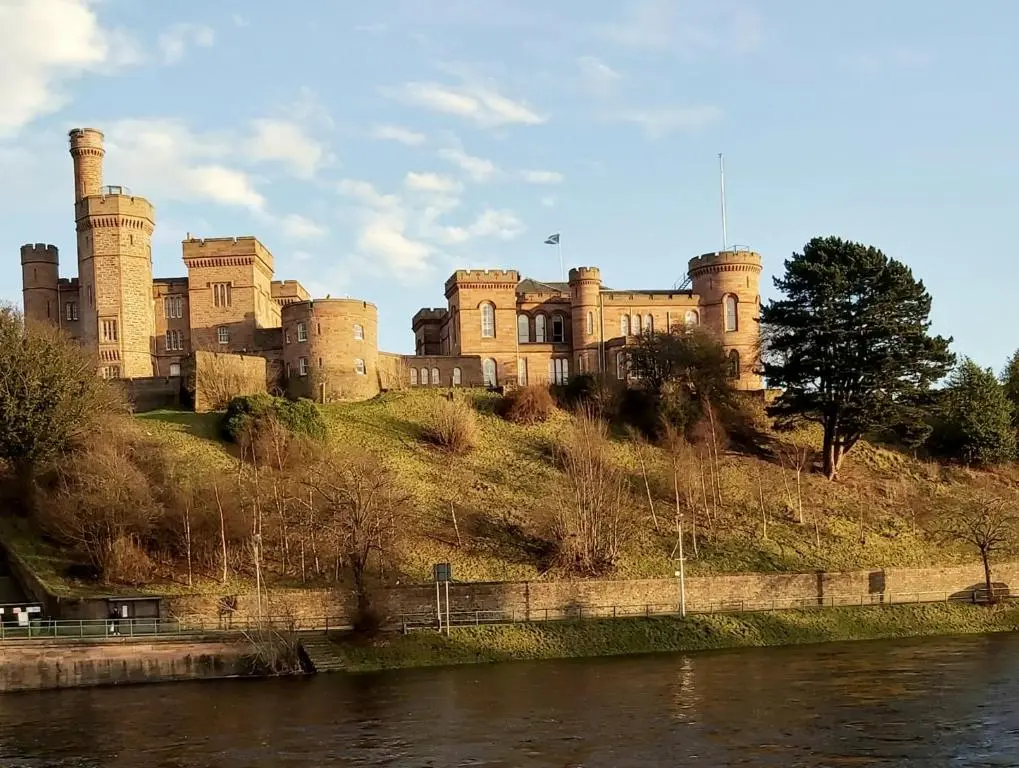 a castle on top of a hill next to a river at Inverness City Centre Apartment with Elevator and Google Chromecast in Inverness
