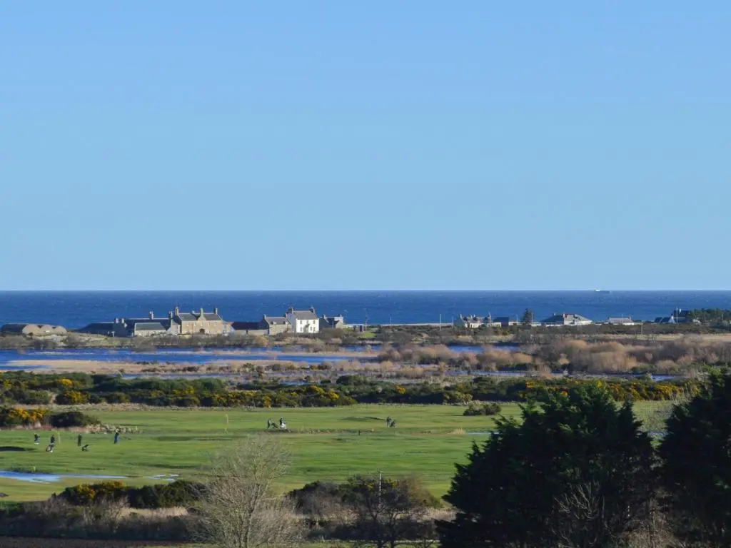 a view of a golf course with the ocean in the background at March Brown in Garmouth