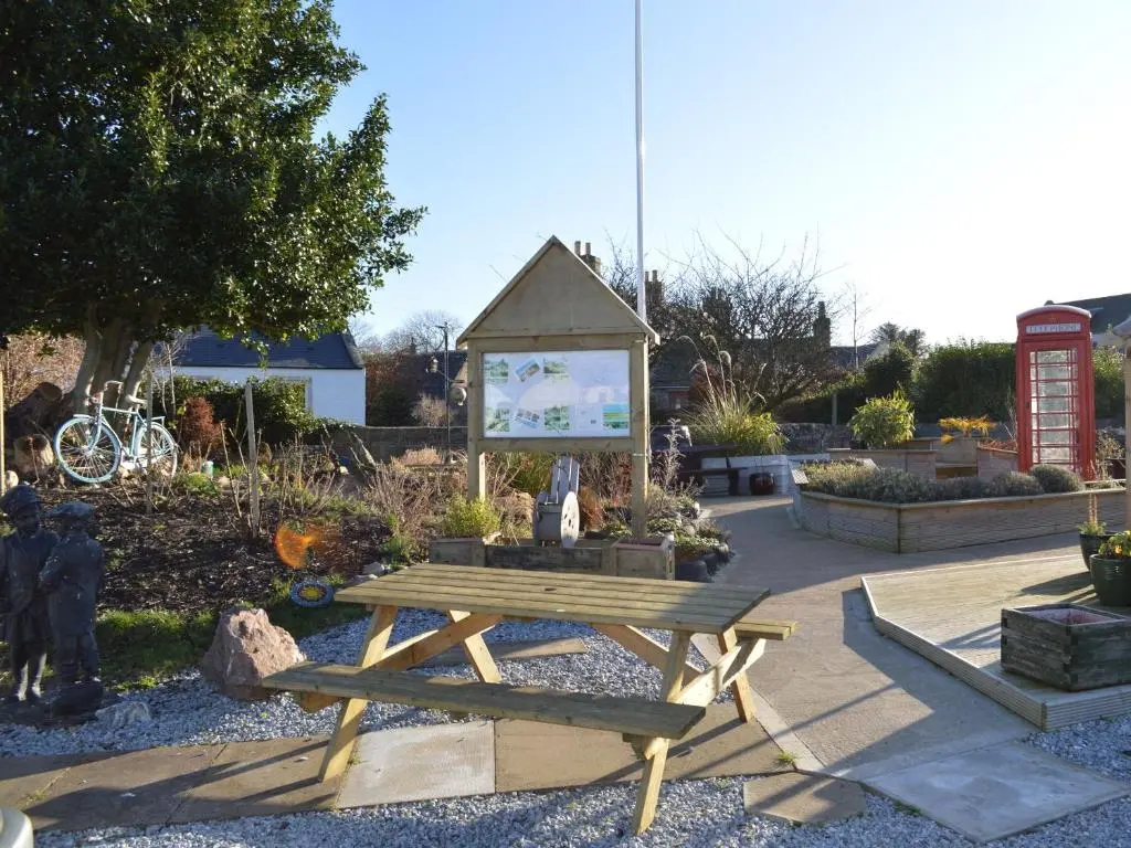 a picnic table and a sign in a garden at March Brown in Garmouth