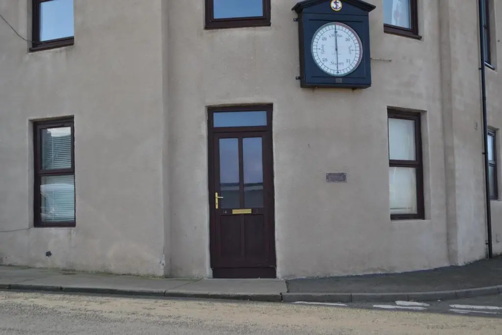 a clock on the side of a building with a door at Harbour View Apartment Wick in Wick