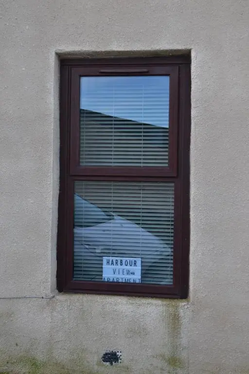 a window with a sign that says hang out my window at Harbour View Apartment Wick in Wick