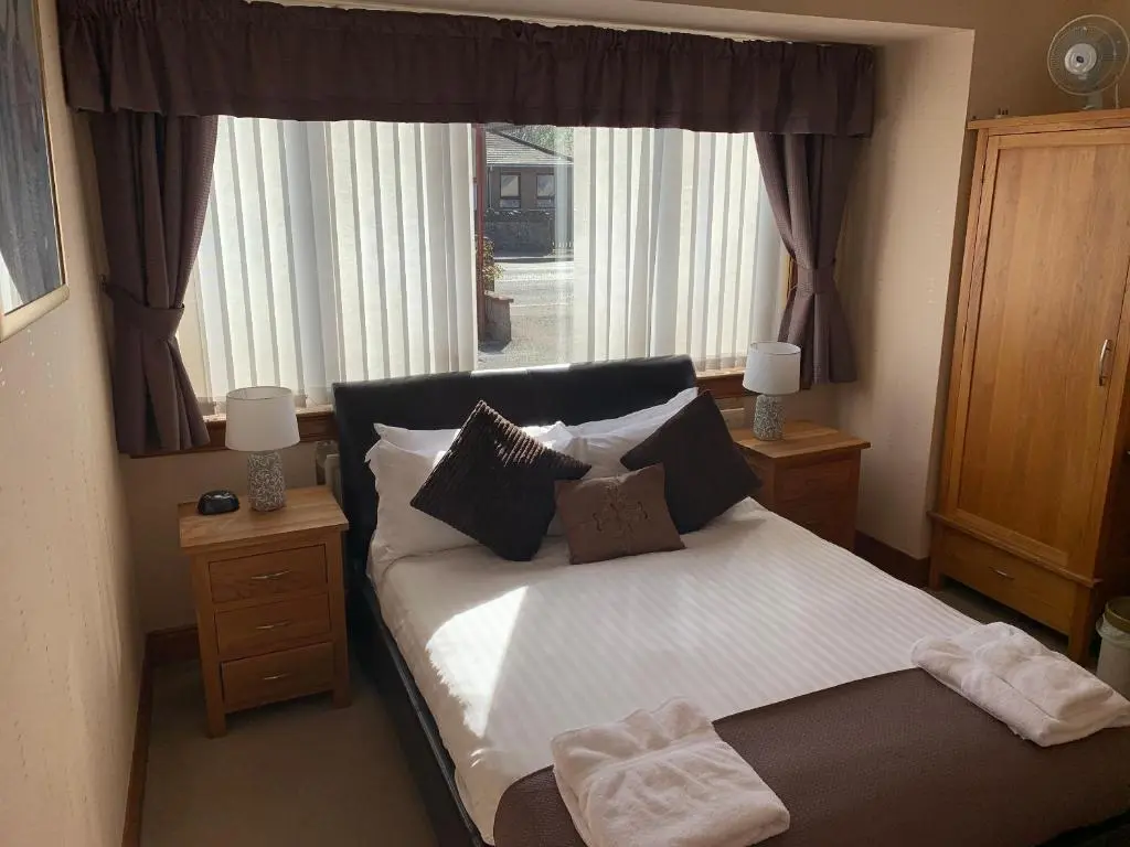 a bedroom with a bed with pillows and a window at Lyndon Guest House in Inverness