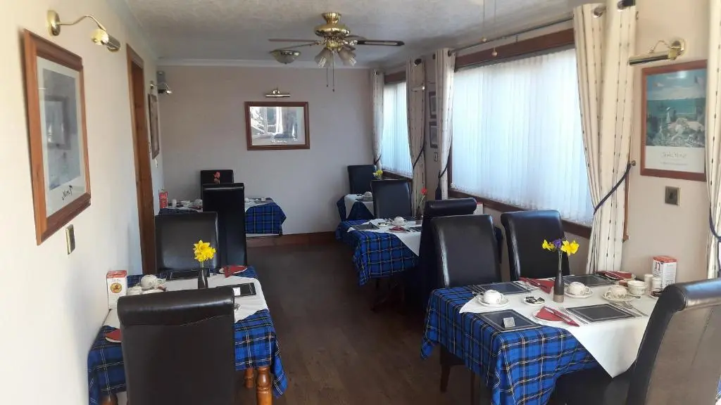 a restaurant with two tables and chairs and a ceiling at Lyndon Guest House in Inverness