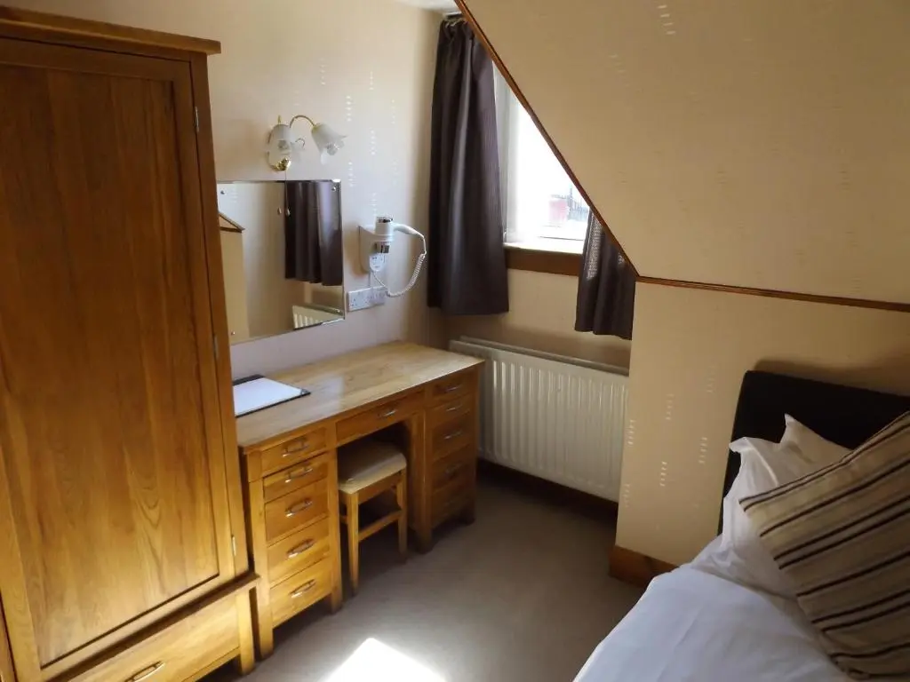 a bedroom with a vanity with a mirror and a bed at Lyndon Guest House in Inverness