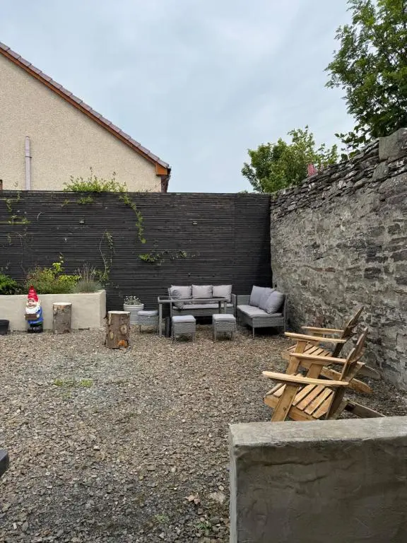 a patio with couches and chairs next to a wall at Church view in Wick