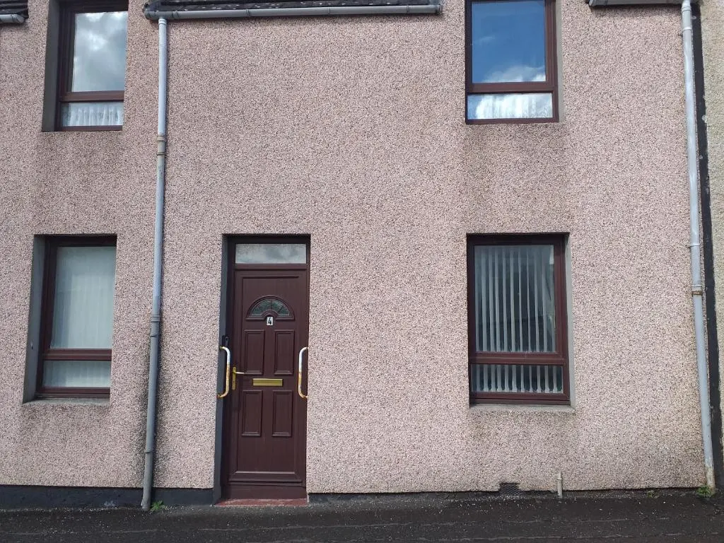 a building with a brown door and two windows at Church view in Wick