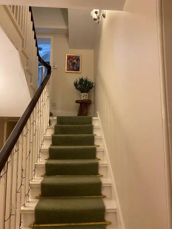 a staircase with green carpeting and a green rug at Tullich House in Keith