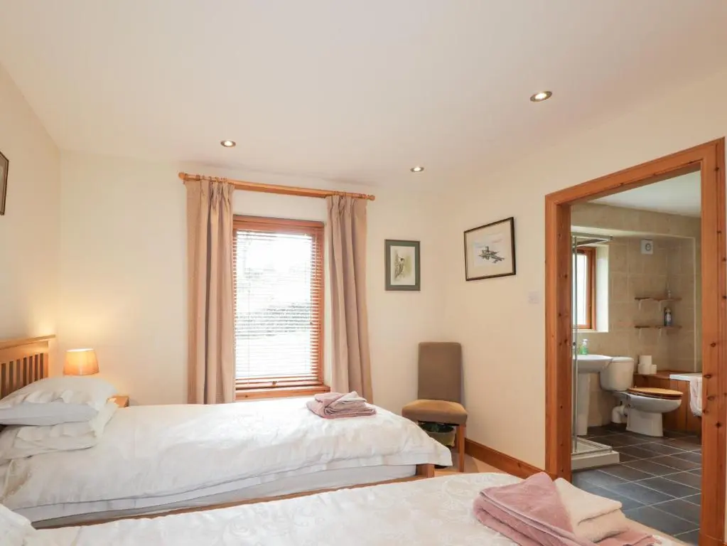 a bedroom with a bed and a bathroom with a mirror at An Torr in Newtonmore