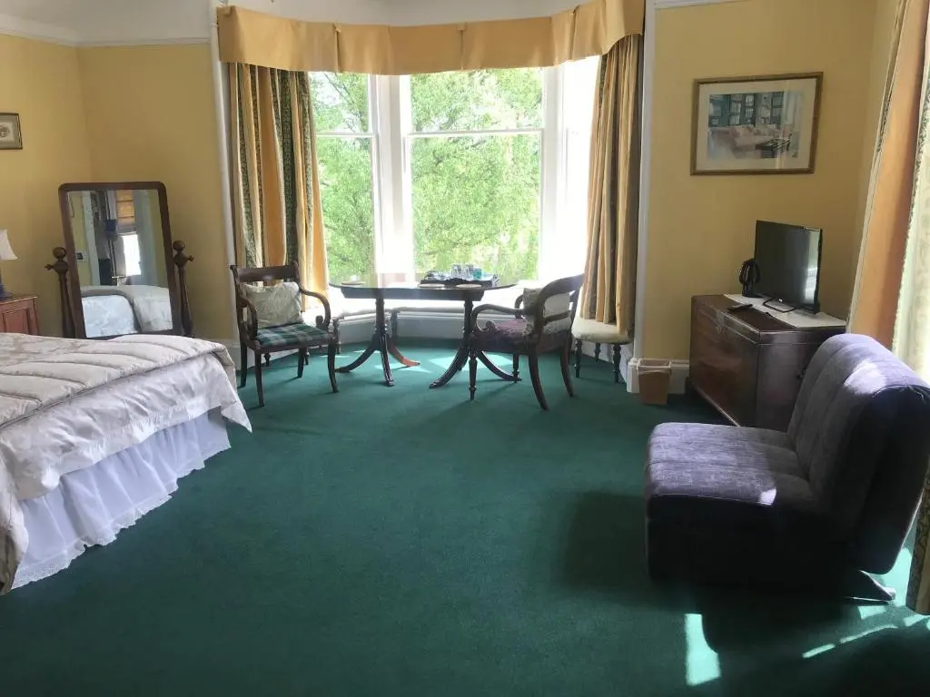 a bedroom with a bed and a table and chairs at Kilmorie House in Elgin