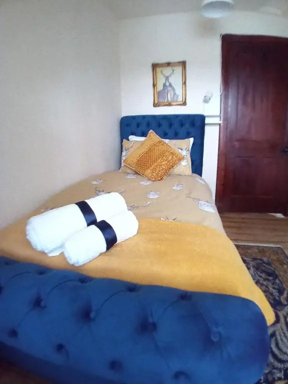a bedroom with a blue bed with towels on it at The Granary in The Square in Grantown on Spey