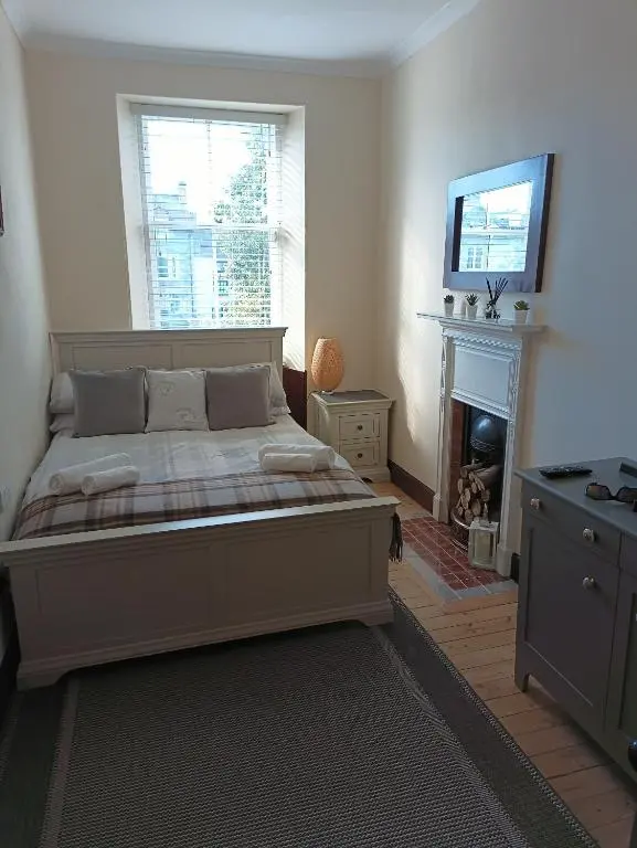 a bedroom with a bed with a fireplace and a television at The Granary in The Square in Grantown on Spey