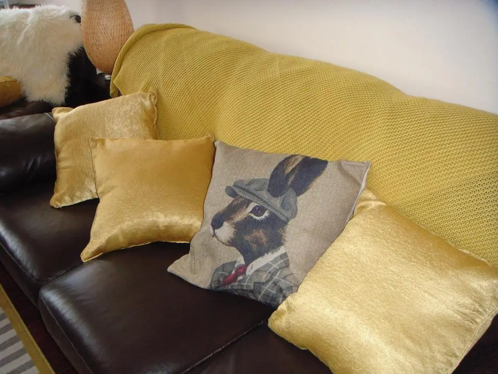 a couch with a pillow with a dog wearing a hat at The Granary in The Square in Grantown on Spey
