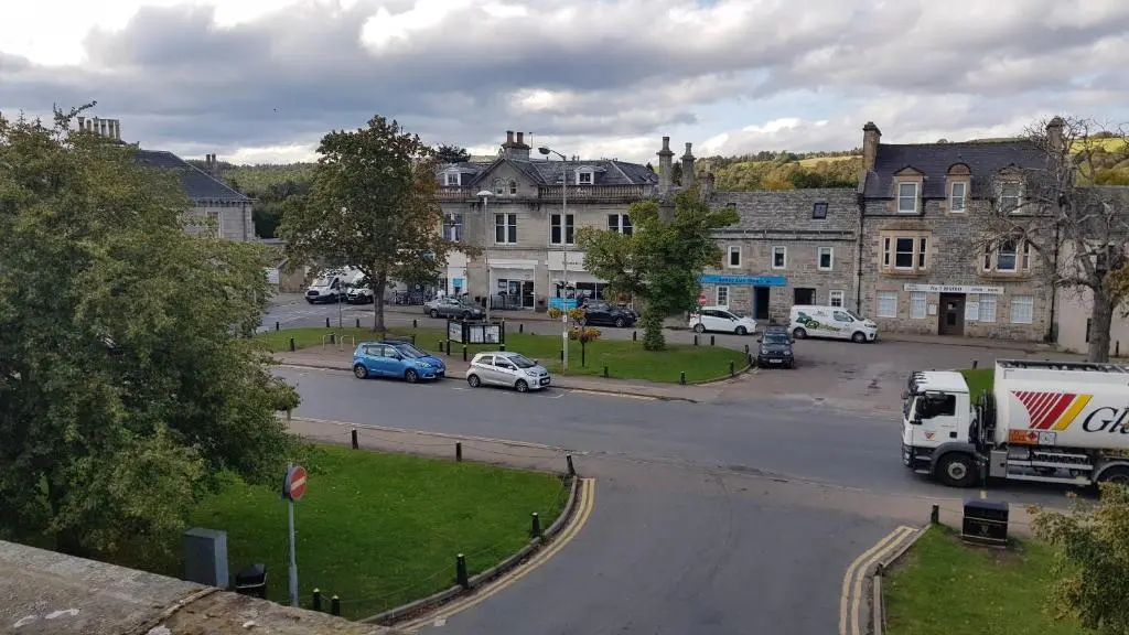 a city street with cars parked on the road at The Granary in The Square in Grantown on Spey