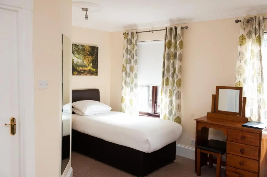 a small bedroom with a bed and a window at Alban and Abbey House in Inverness