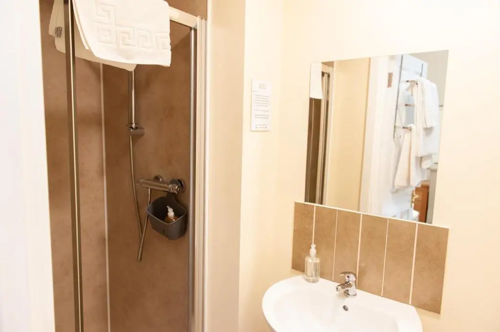 a bathroom with a sink and a shower with a mirror at Alban and Abbey House in Inverness