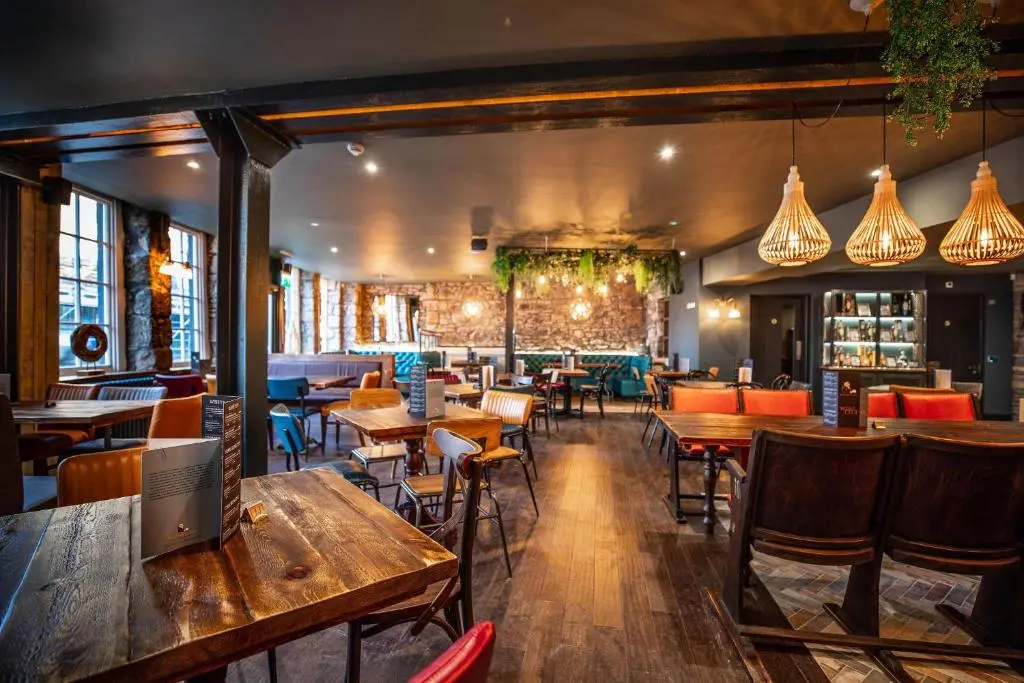 a restaurant with wooden tables and chairs and a bar at Blackfriars in Inverness