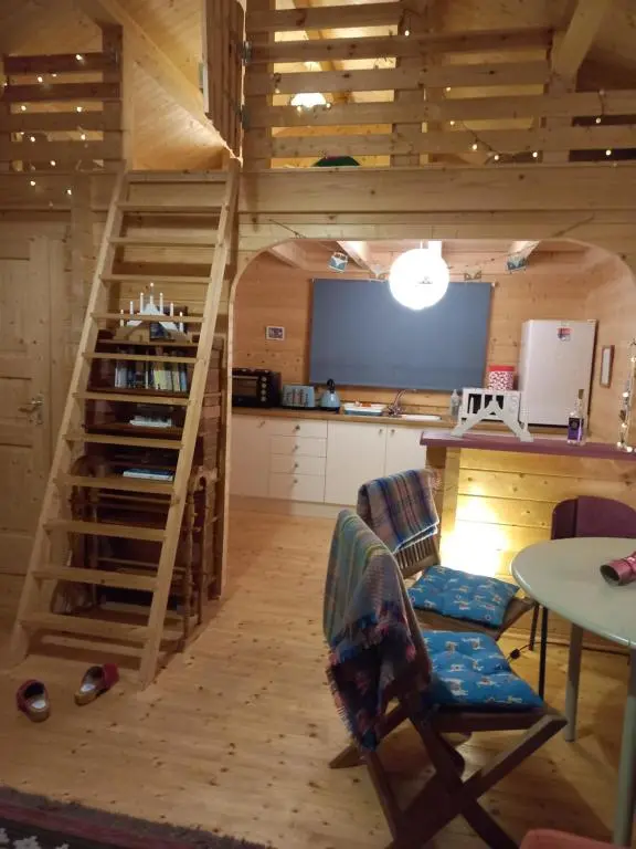 a living room with a staircase and a kitchen at Springbank Cabin in Insch