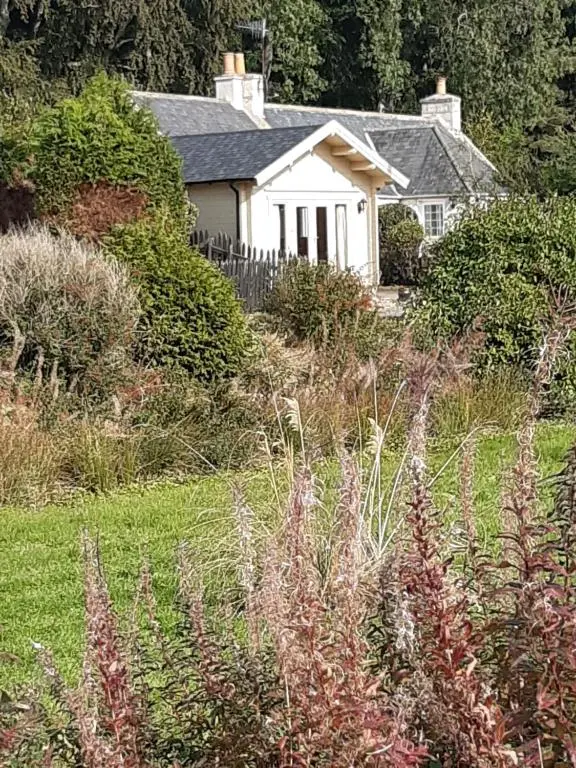 a white house in the middle of a field at Springbank Cabin in Insch
