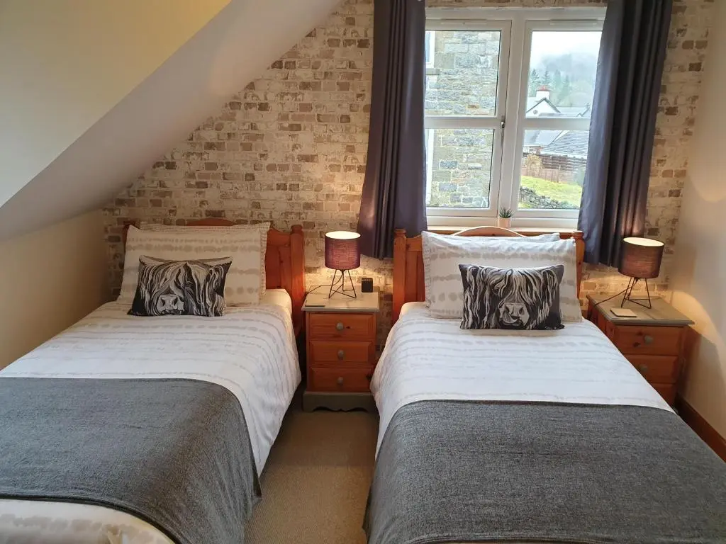 two beds in a room with two windows at Lorien House B&B in Fort Augustus