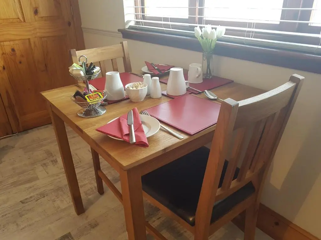 a wooden table with a red napkin on it at Lorien House B&B in Fort Augustus