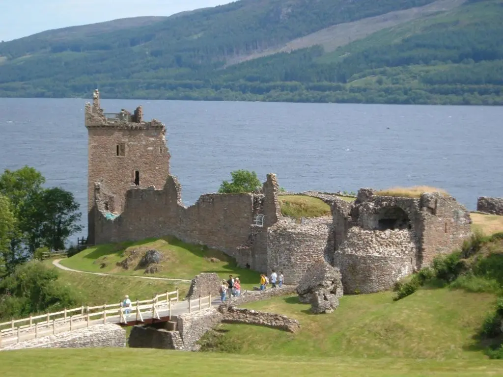 a castle on a hill next to a body of water at Lorien House B&B in Fort Augustus