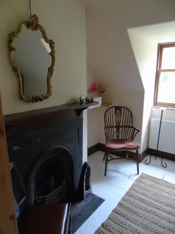 a living room with a fireplace and a mirror on the wall at Stable Cottage, CrannachCottages in Garve