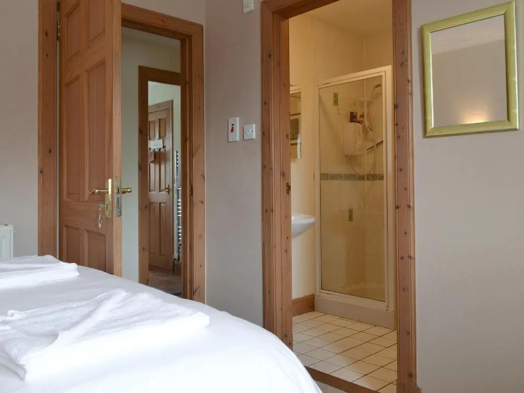 a bedroom with a bed and a bathroom with a shower at Rowan Cottage in Aviemore
