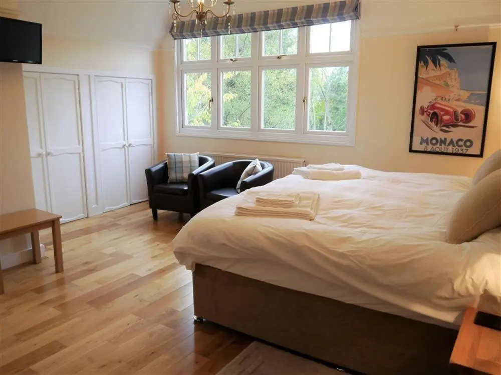 a bedroom with a large bed and a chair and window at Shieling Beag in Banchory