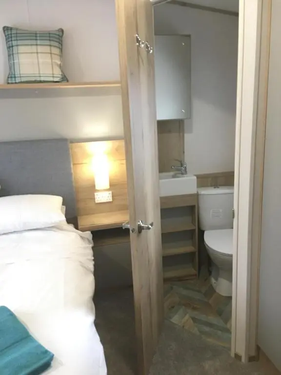 a bathroom with a bed and a sink and a toilet at Bynack Lodge in Boat of Garten
