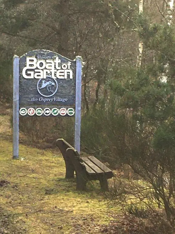 a sign sitting next to a bench next to a sign at Bynack Lodge in Boat of Garten