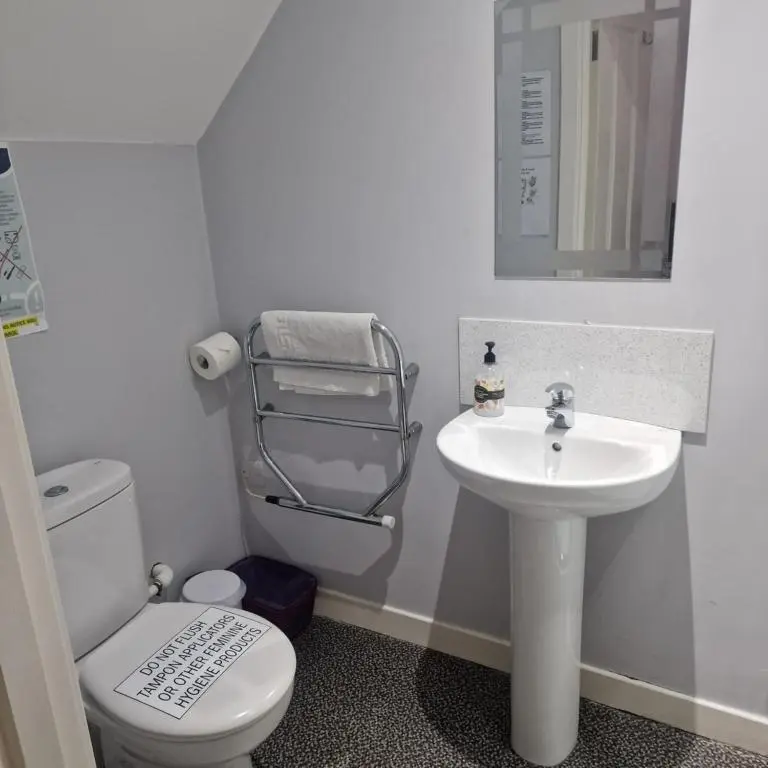 a white bathroom with a toilet and a sink at Black Isle Holiday Apartments in Avoch